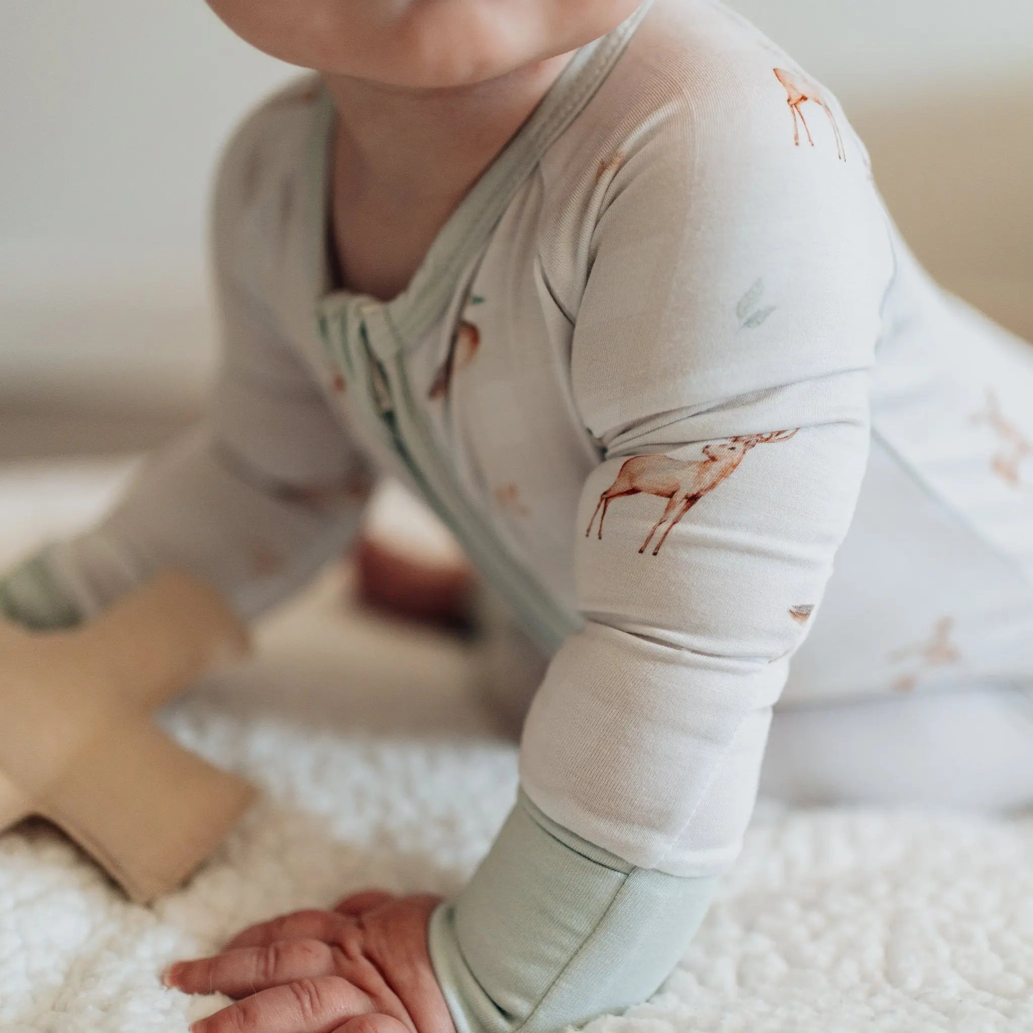 Baby in light-colored outfit with animal pattern on a soft surface