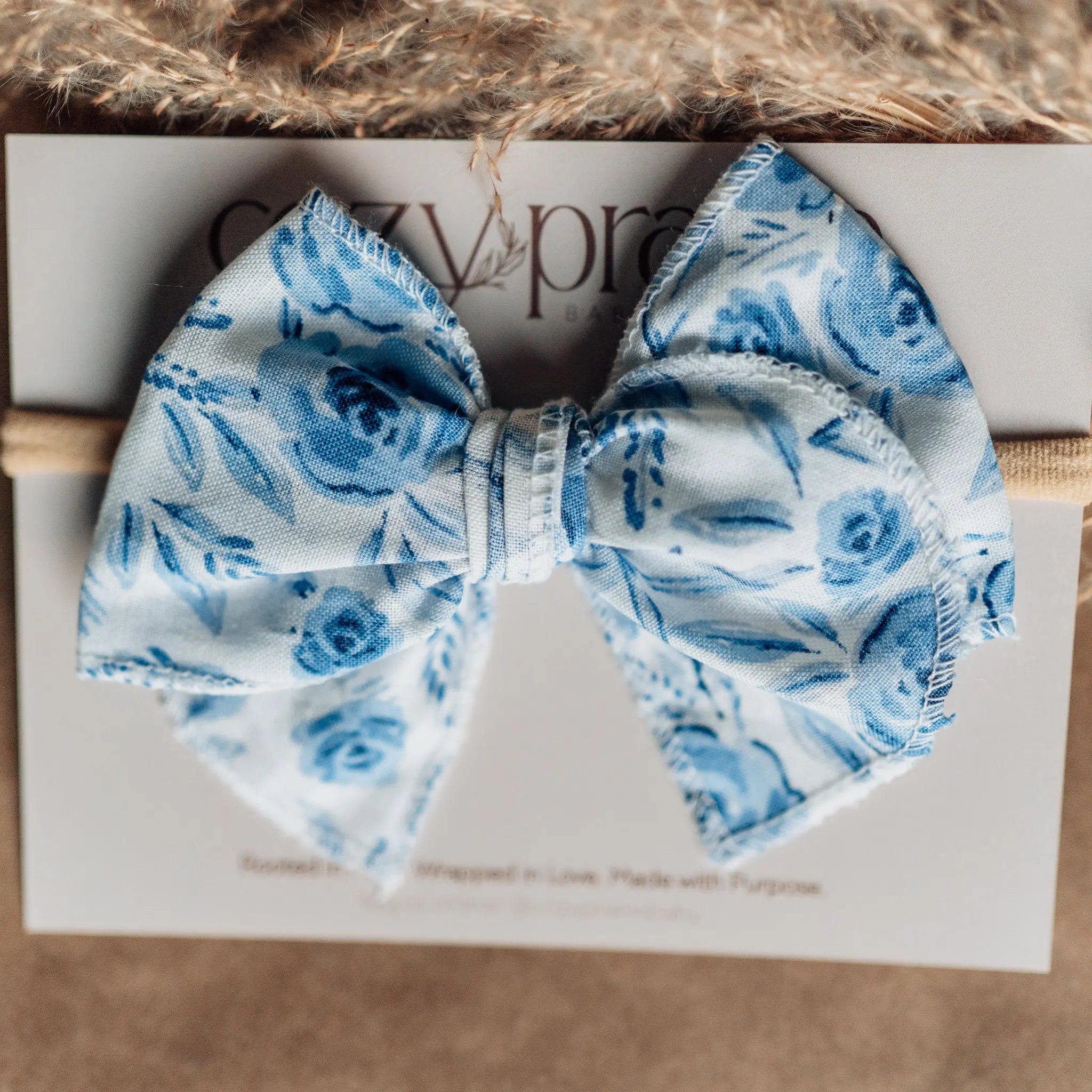 Blue floral bow on a white card with a brown background