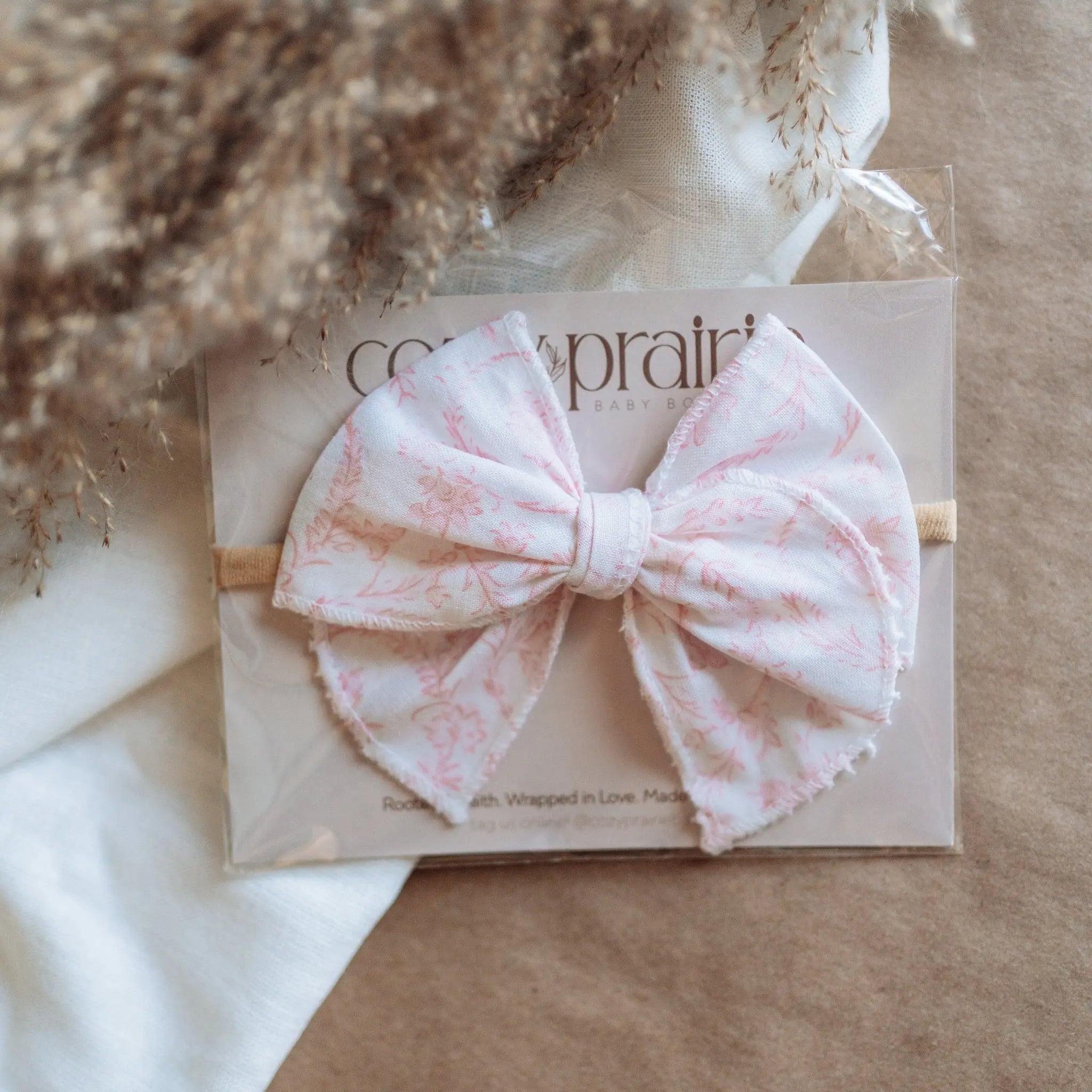 Pink bow headband on a beige card with floral background