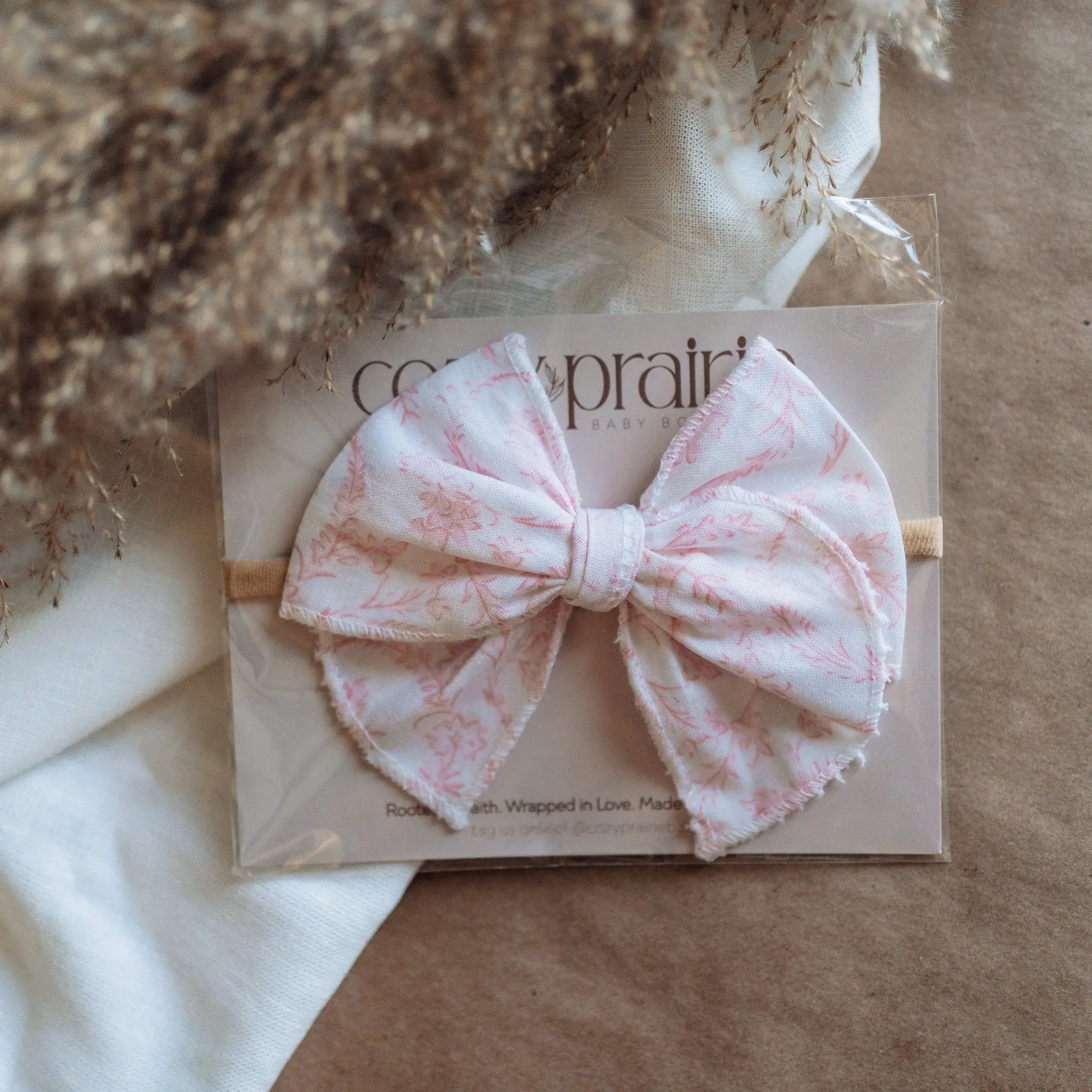 Pink bow headband on a branded card with a textured background