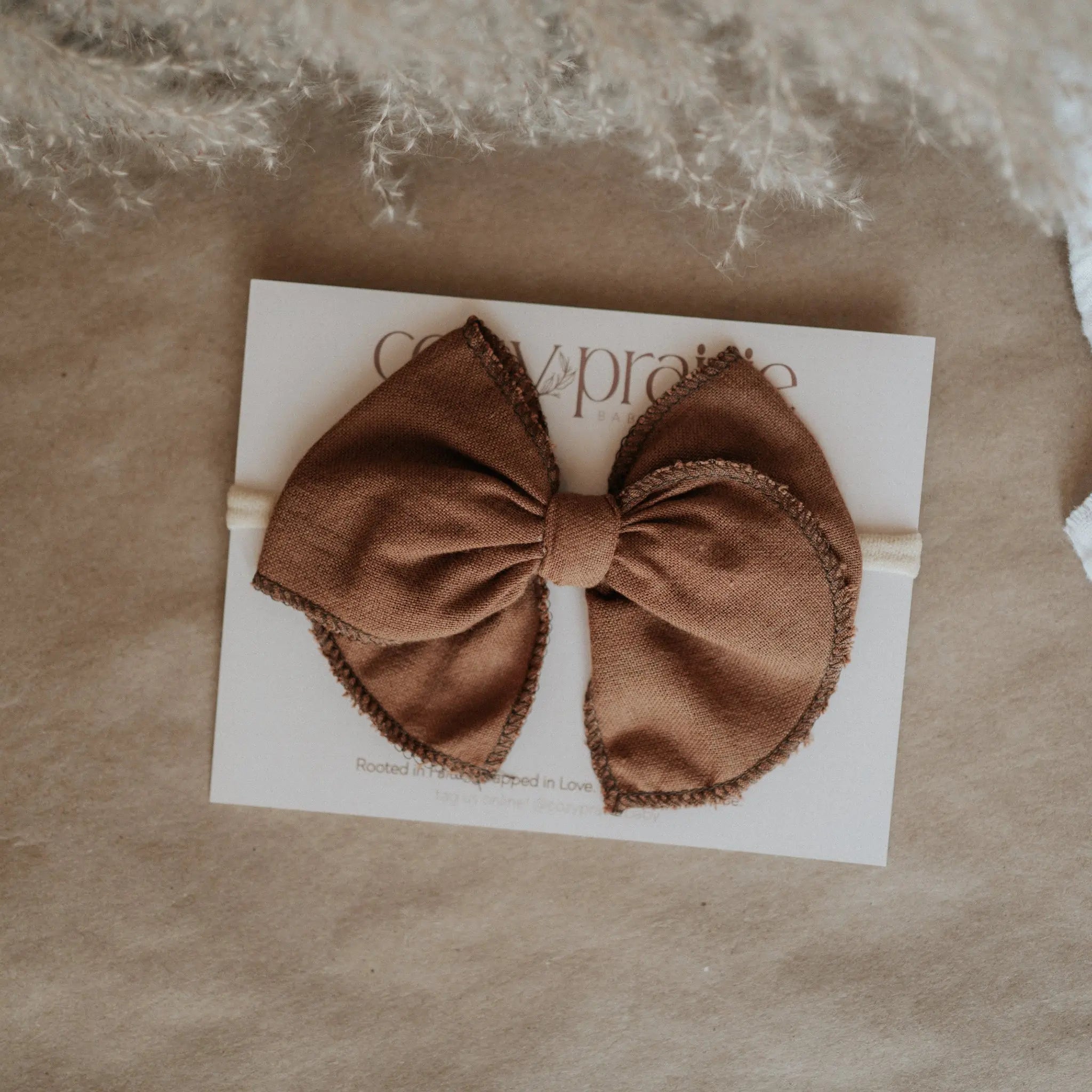 Brown bow hair bow on a beige card with 'Cozy Prairie' branding, placed on brown kraft paper.