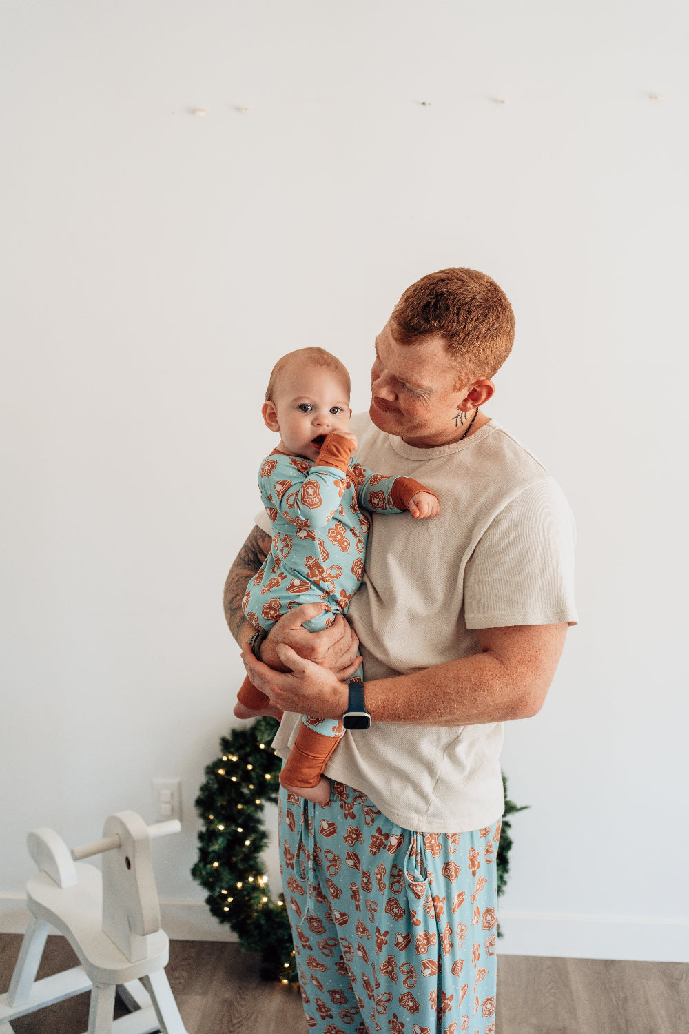 Man holding a baby in a room with a Christmas tree in the background
