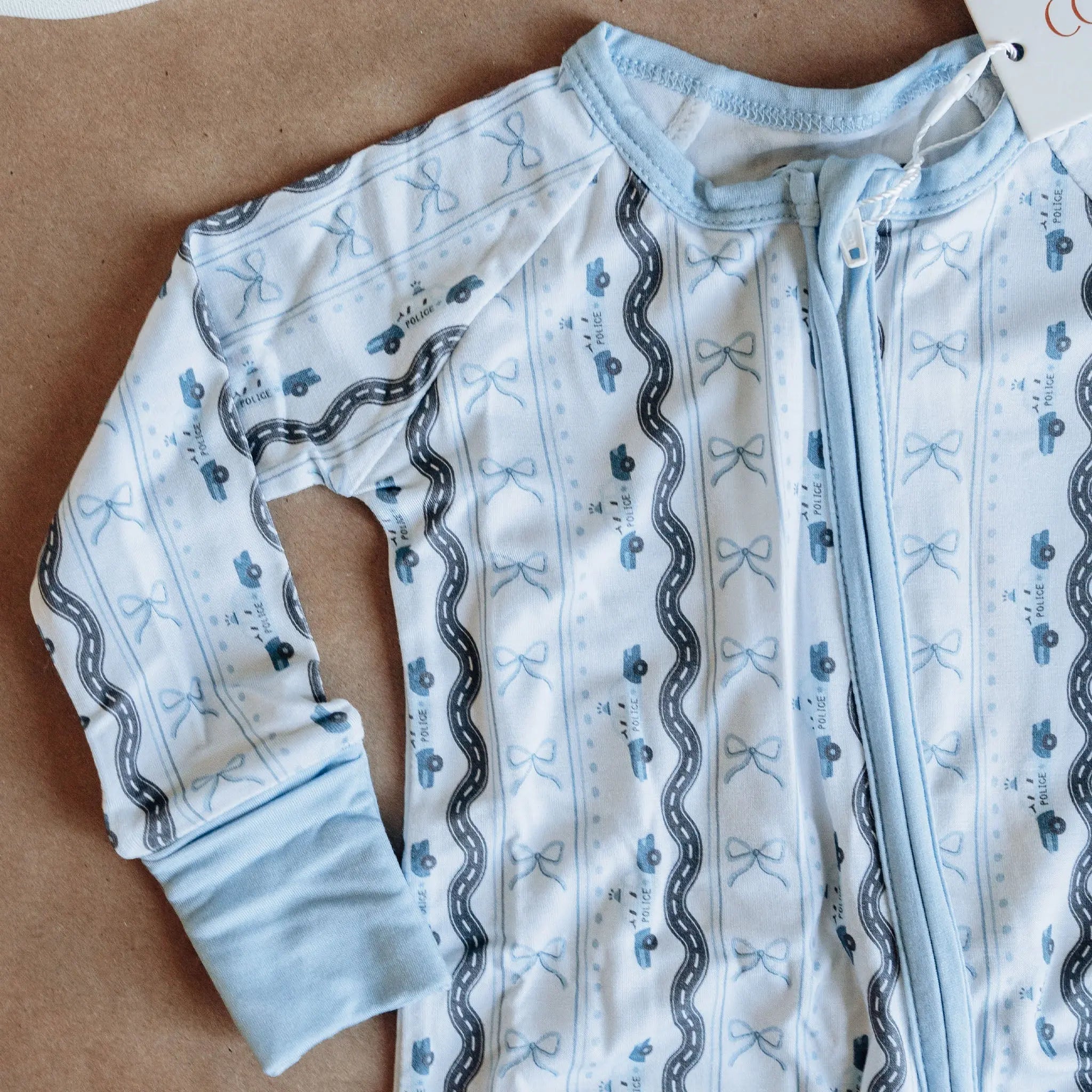 Baby onesie with car pattern on a brown surface.