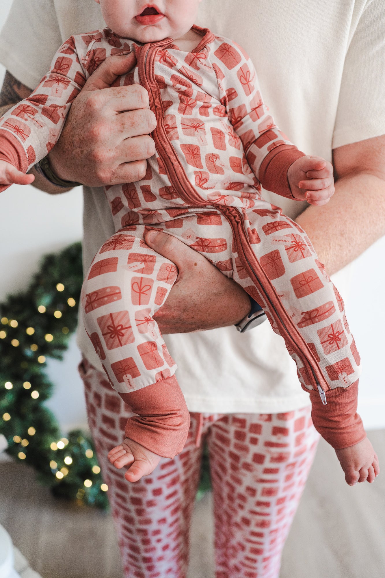 Baby wearing red pajamas being held by man 