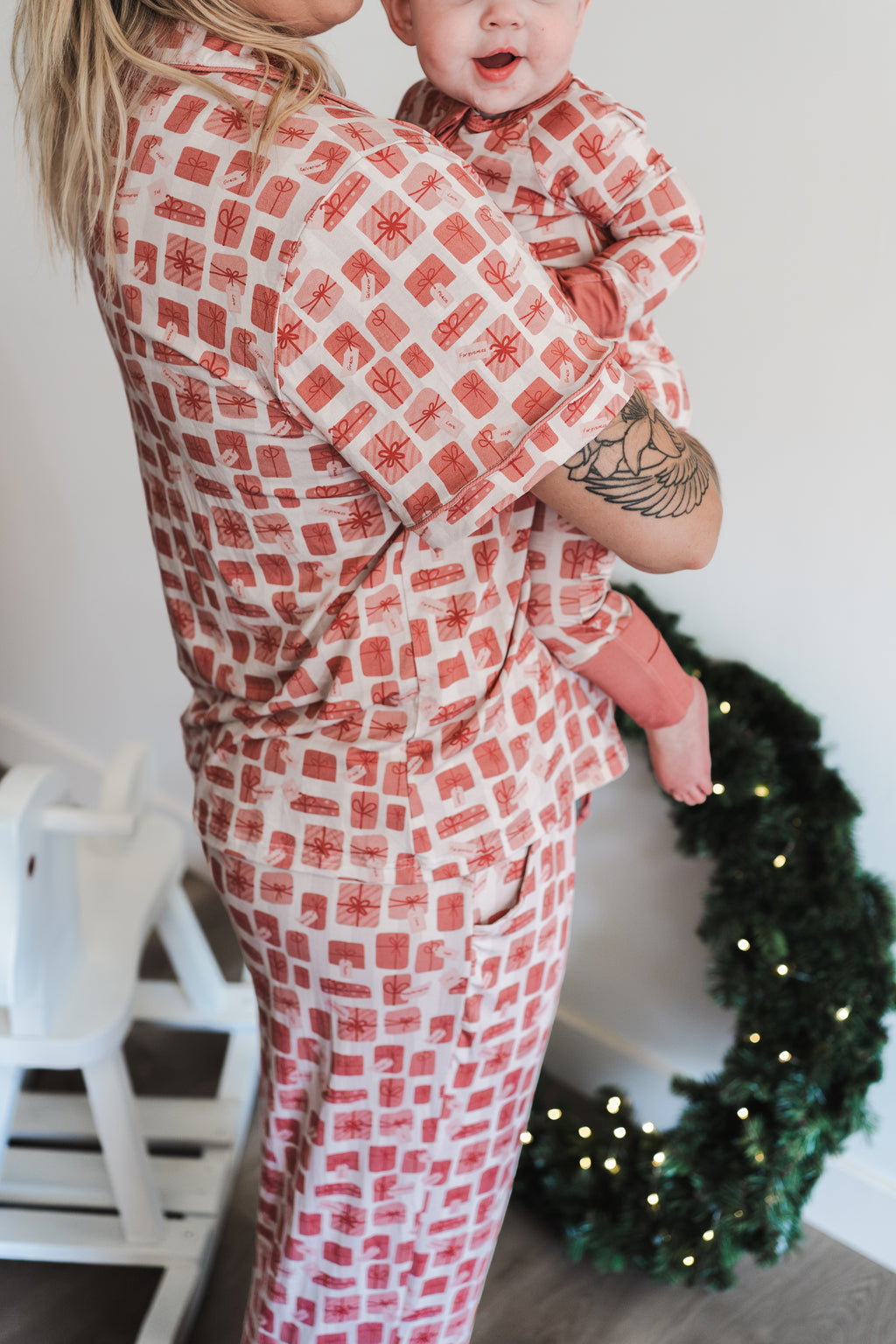Woman and child wearing matching red and white checkered outfits with a Christmas wreath in the background.