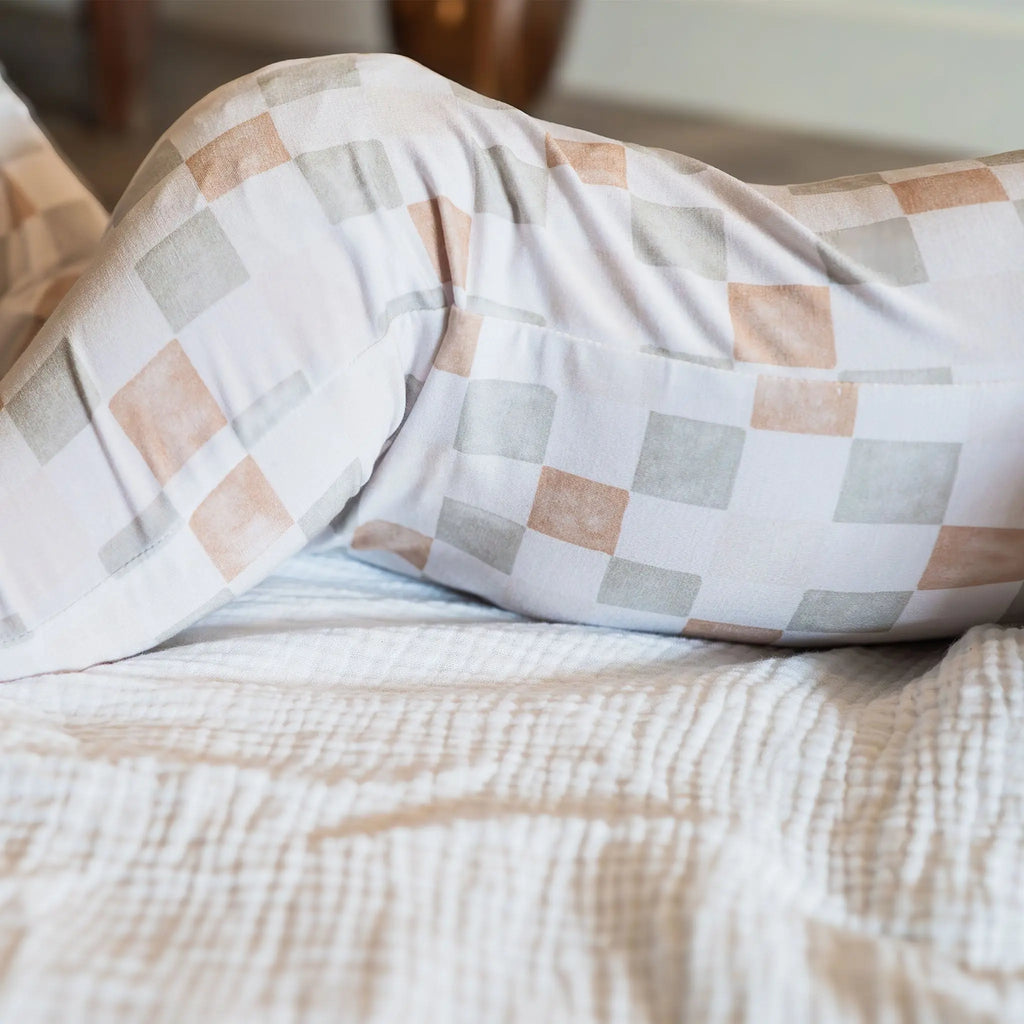 Checkered baby onesie on a bed with a blurred background