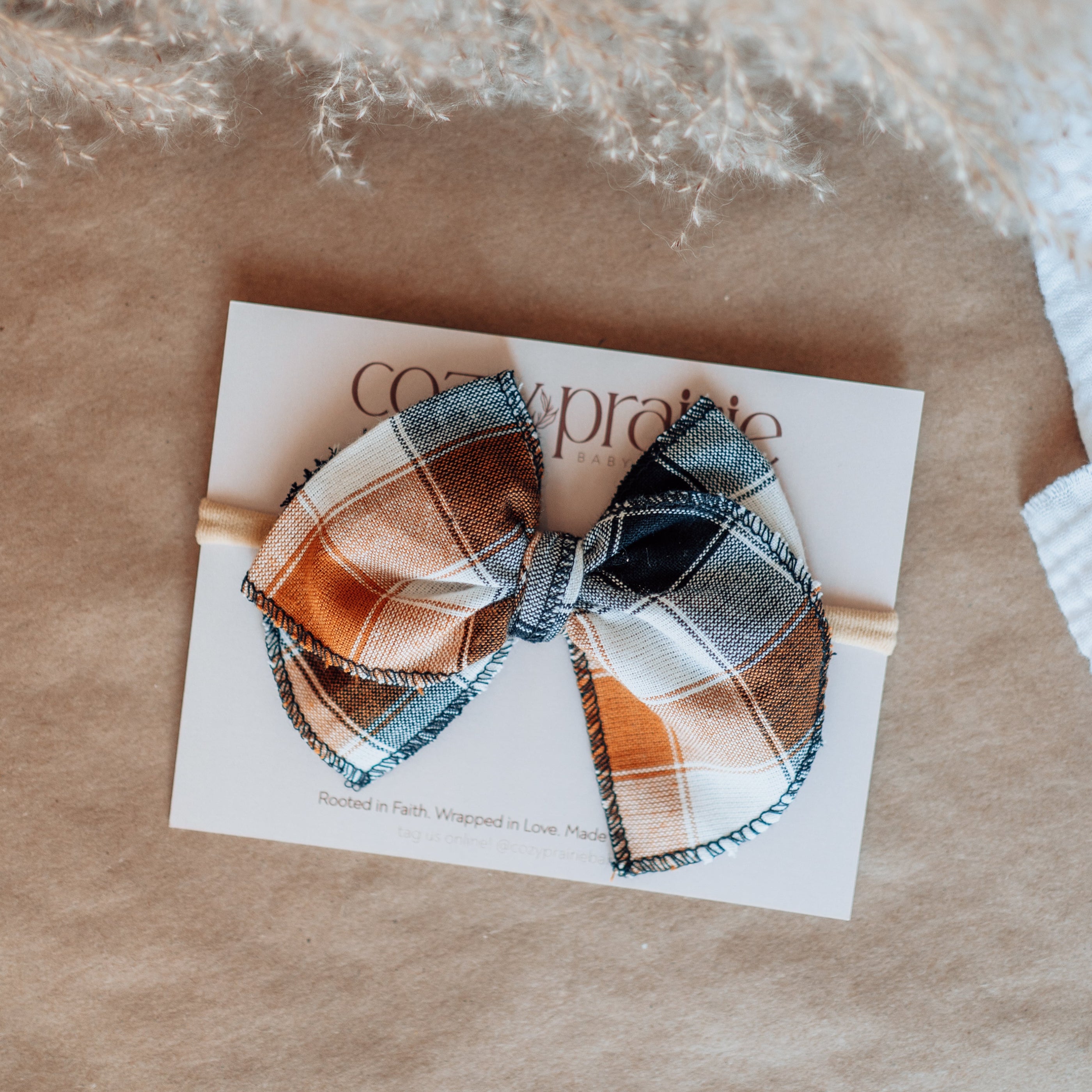 Plaid hair bow on a card with 'Coco & Pipo' branding on a textured surface.