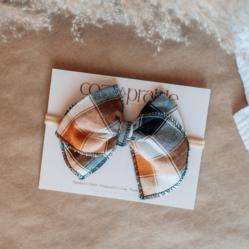 Plaid hair bow on a card with 'Coco & Pipo' branding on a textured surface.