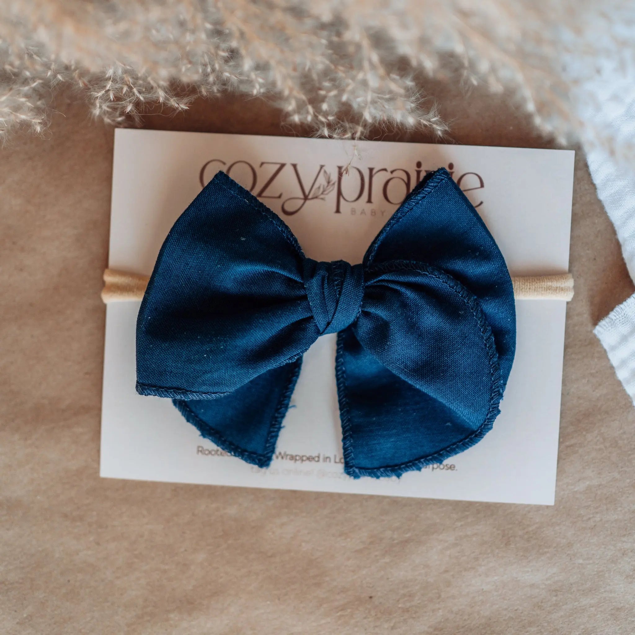 Blue bow hair bow on a Cozy Prairie branded card with a textured background