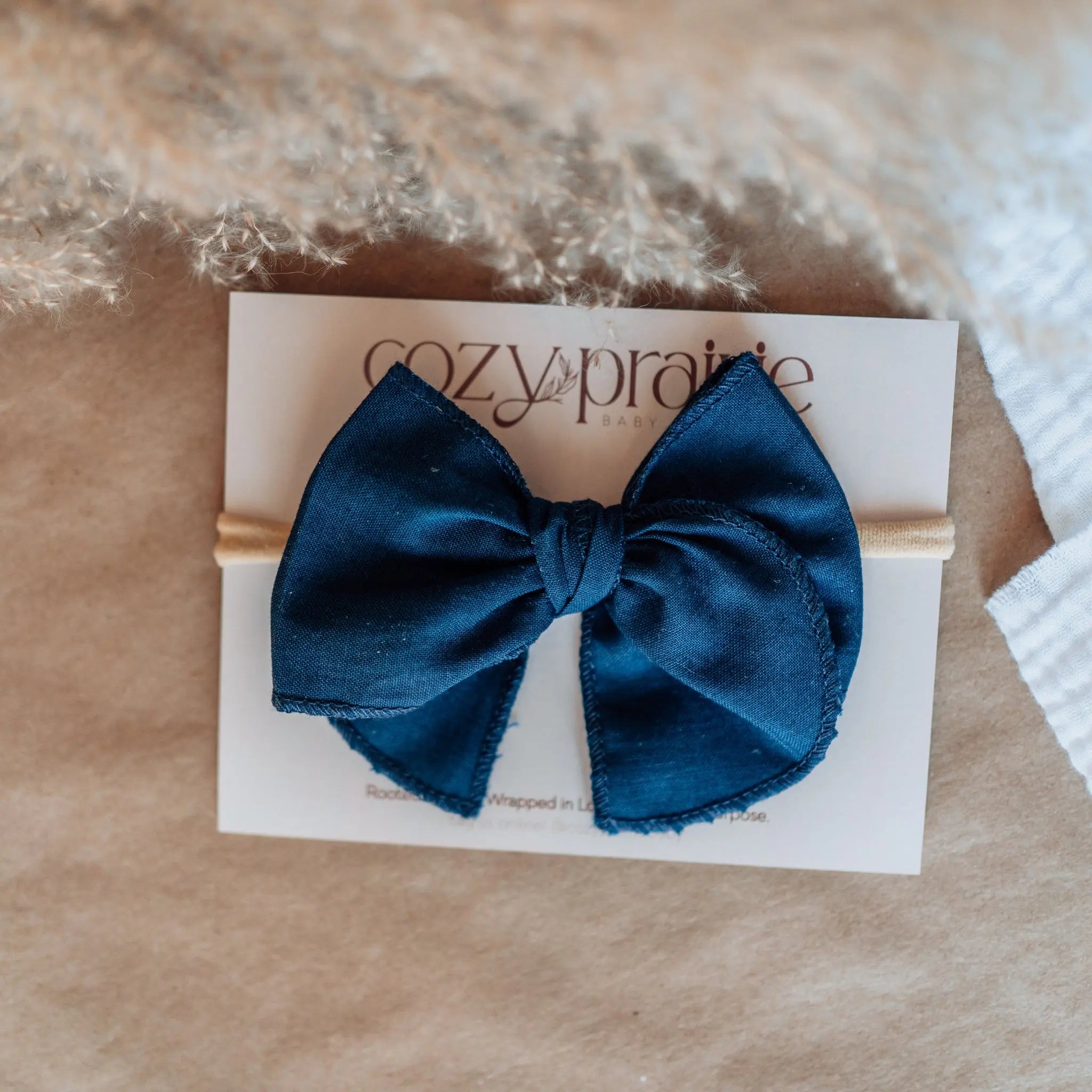 Blue bow on a Cozy Prairie branded card with a textured beige background