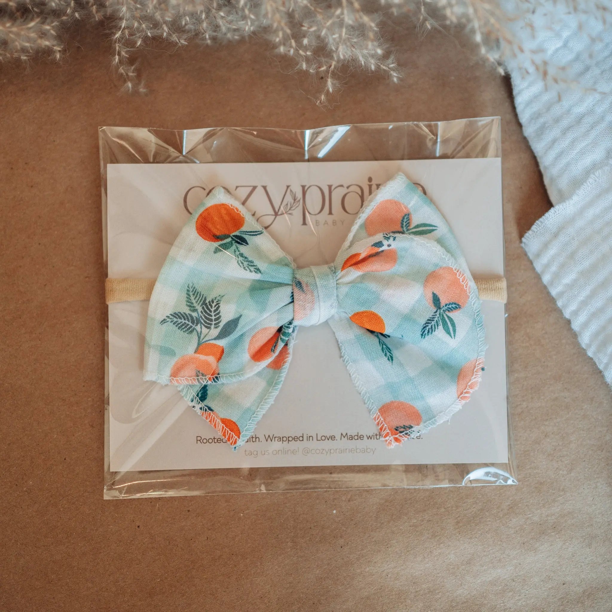 Bow tie with floral design on a clear packaging sheet, placed on a textured surface.