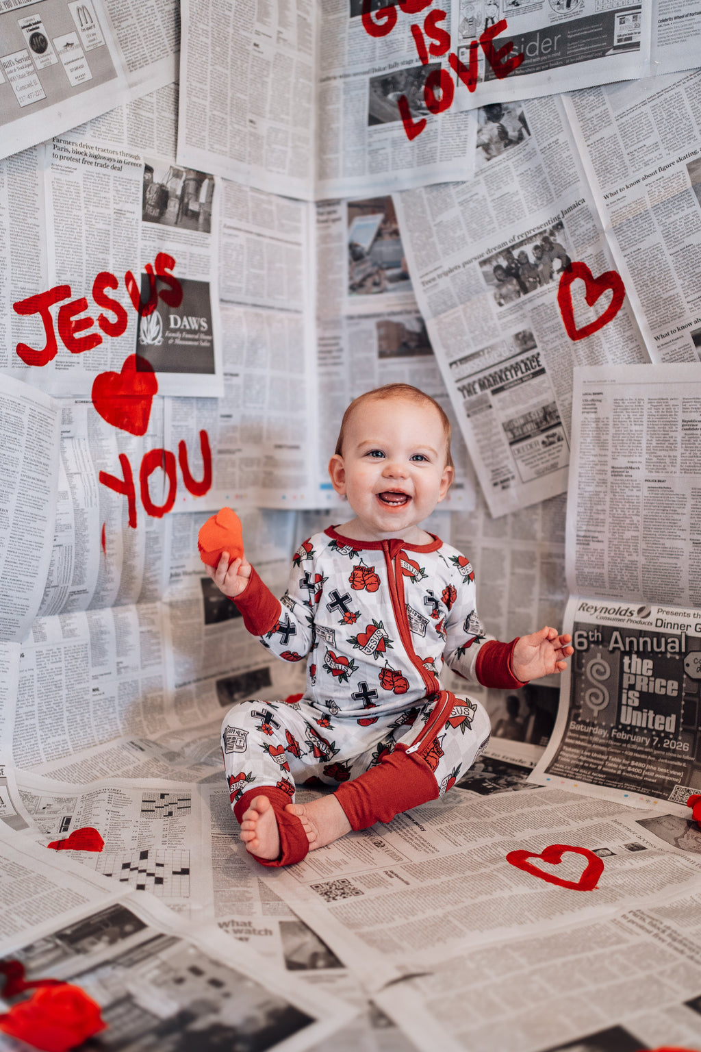 Baby sitting on a newspaper floor with Valentine's Day decorations