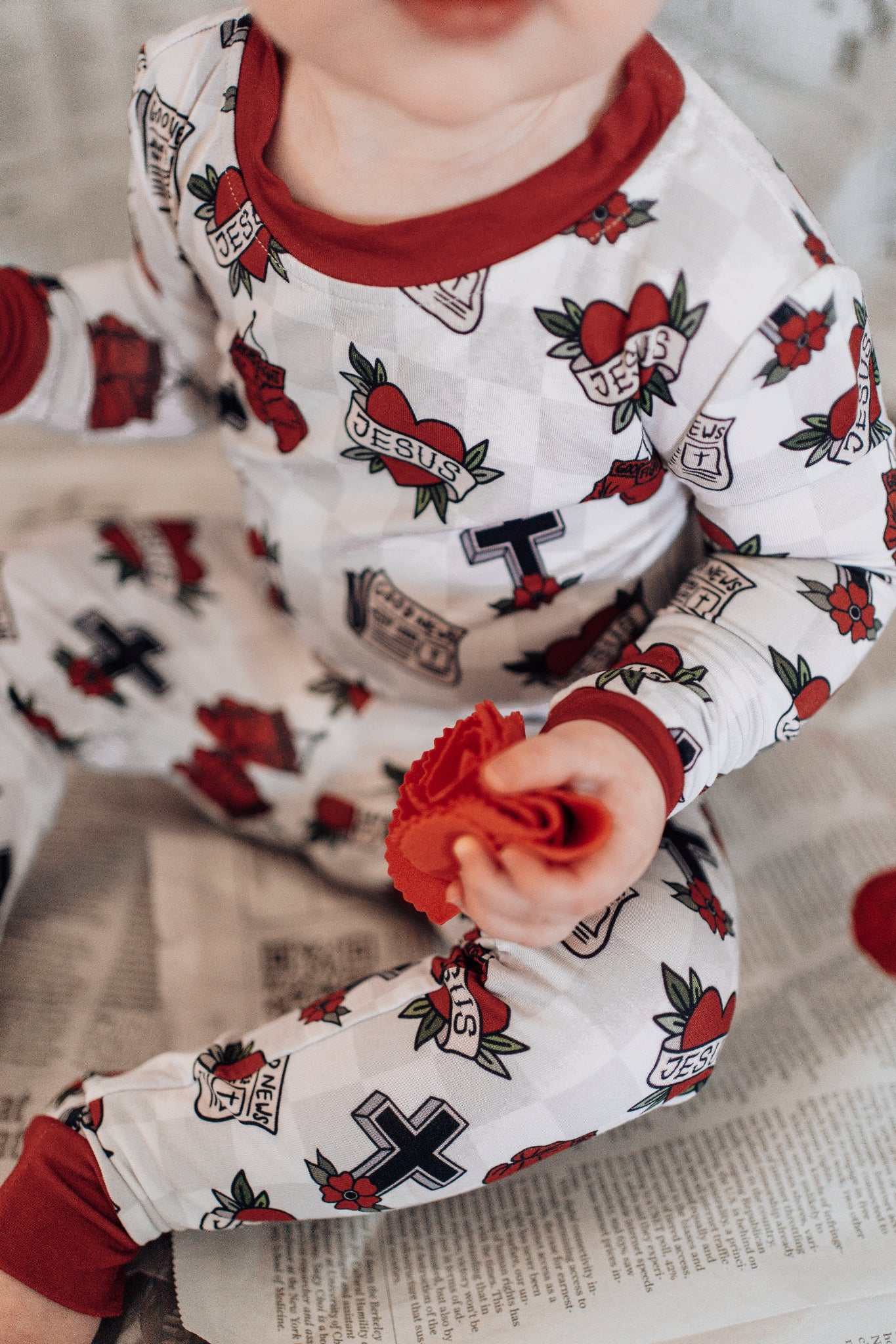 Child wearing pajamas with tattoo-like designs holding a red flower.