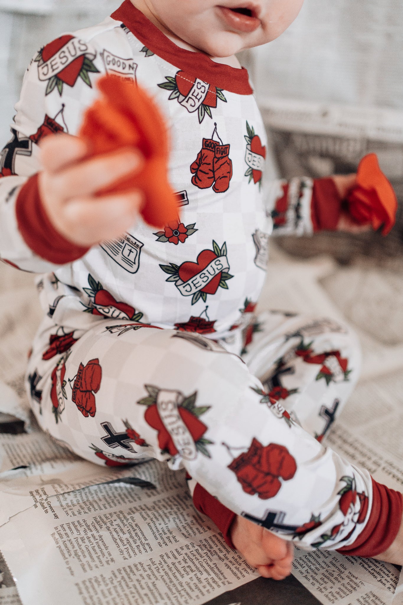 Child wearing a pajama set with tattoo-like designs on a newspaper.