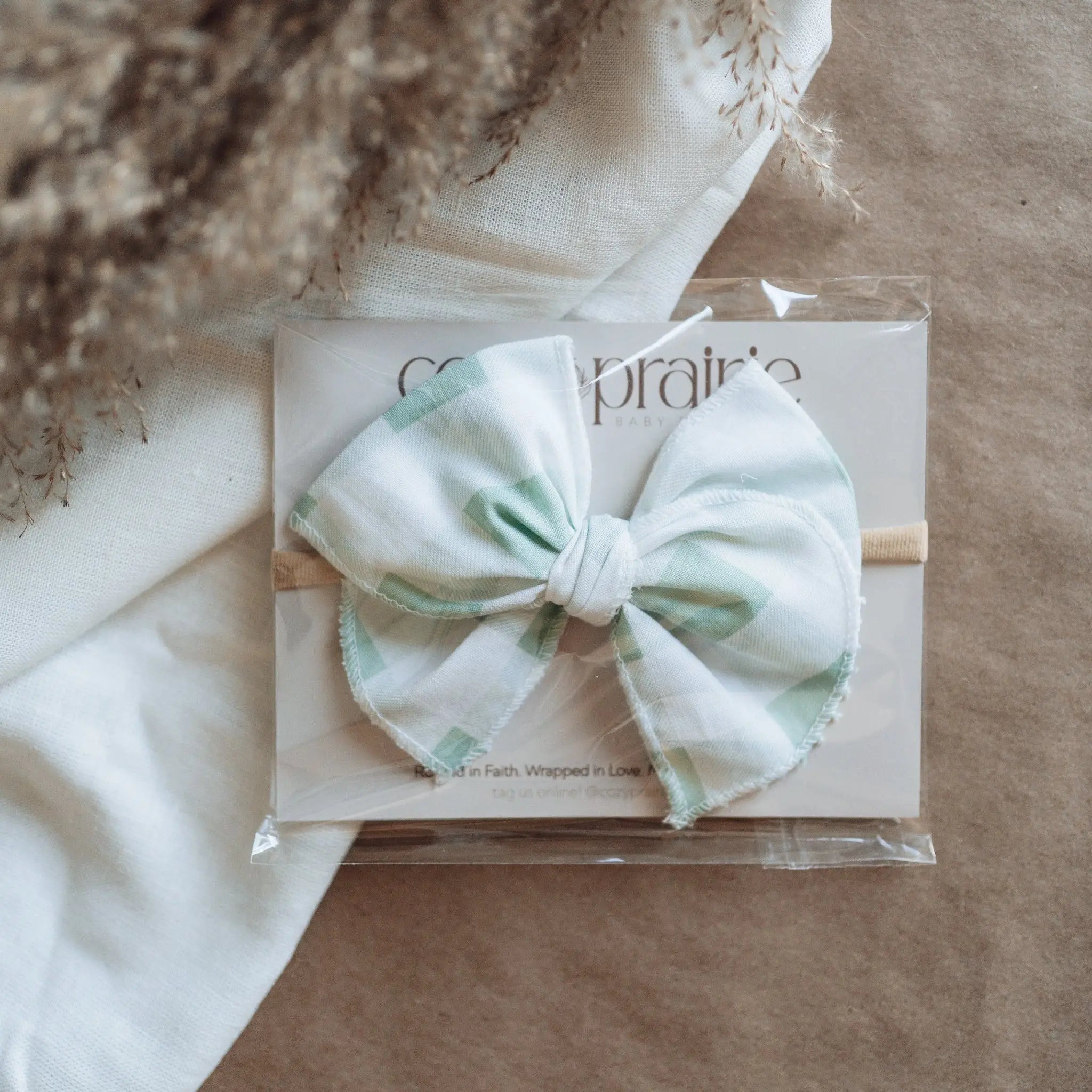 White headband with a bow on a clear plastic sheet against a textured brown background