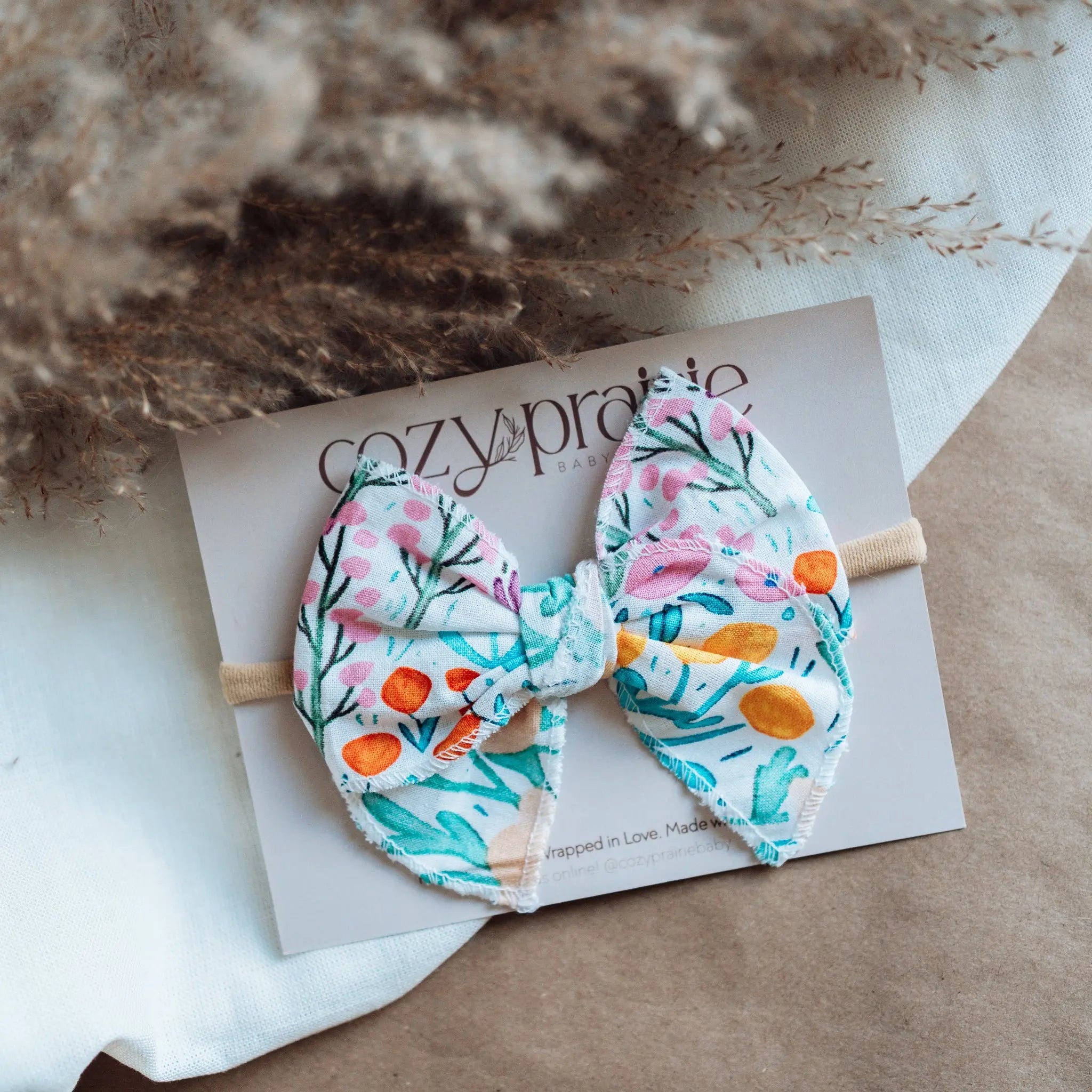 Floral bow hair accessory on a Cozy Prairie card with dried flowers in the background.